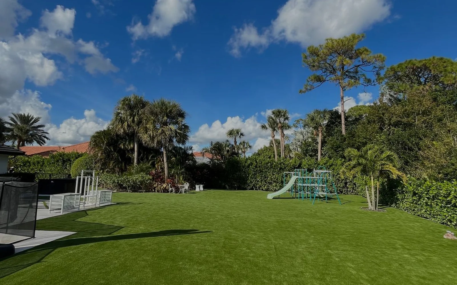 Finished artificial turf backyard with palm trees, pool area and children's play space
