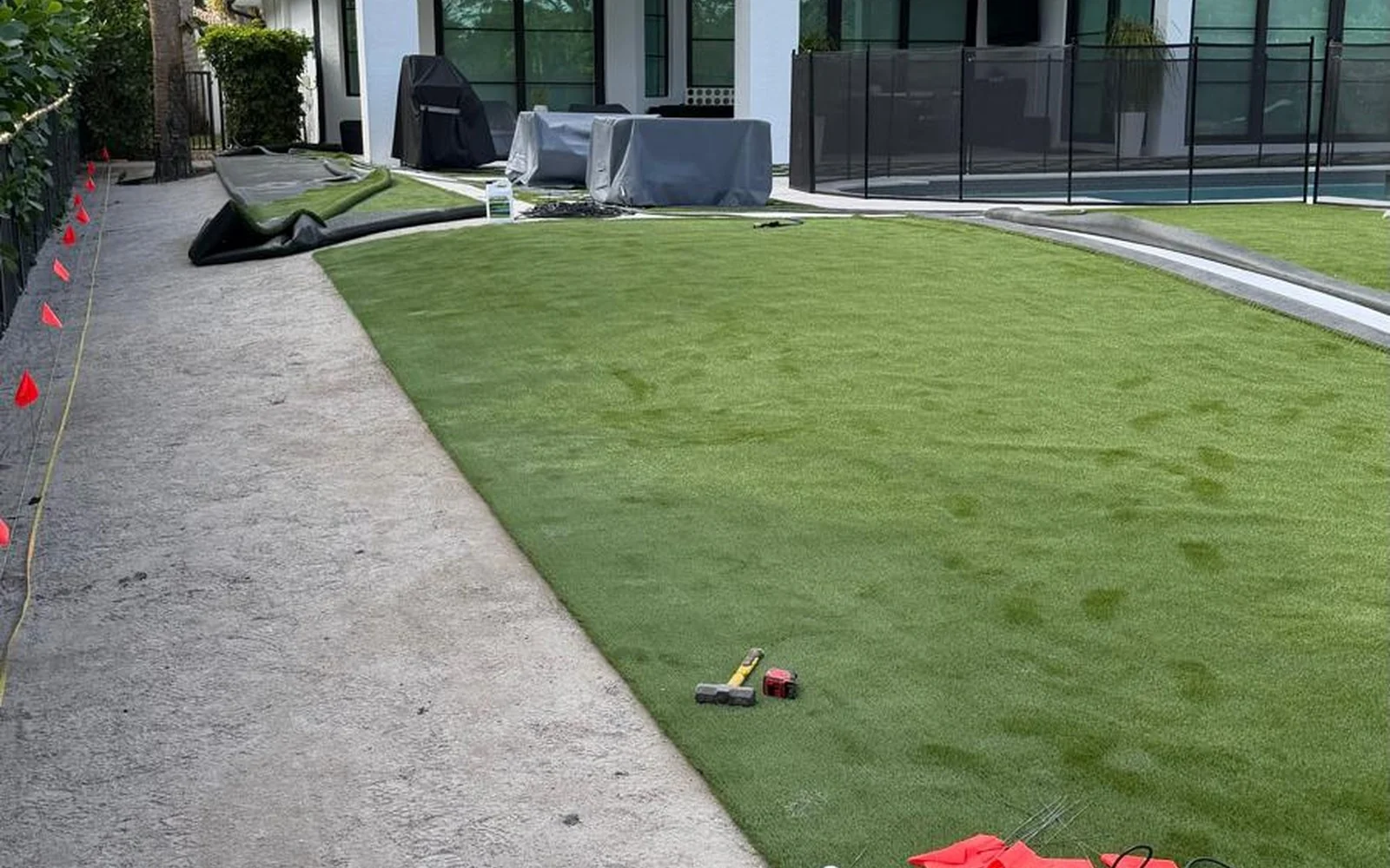 Artificial turf installation in progress beside pool enclosure