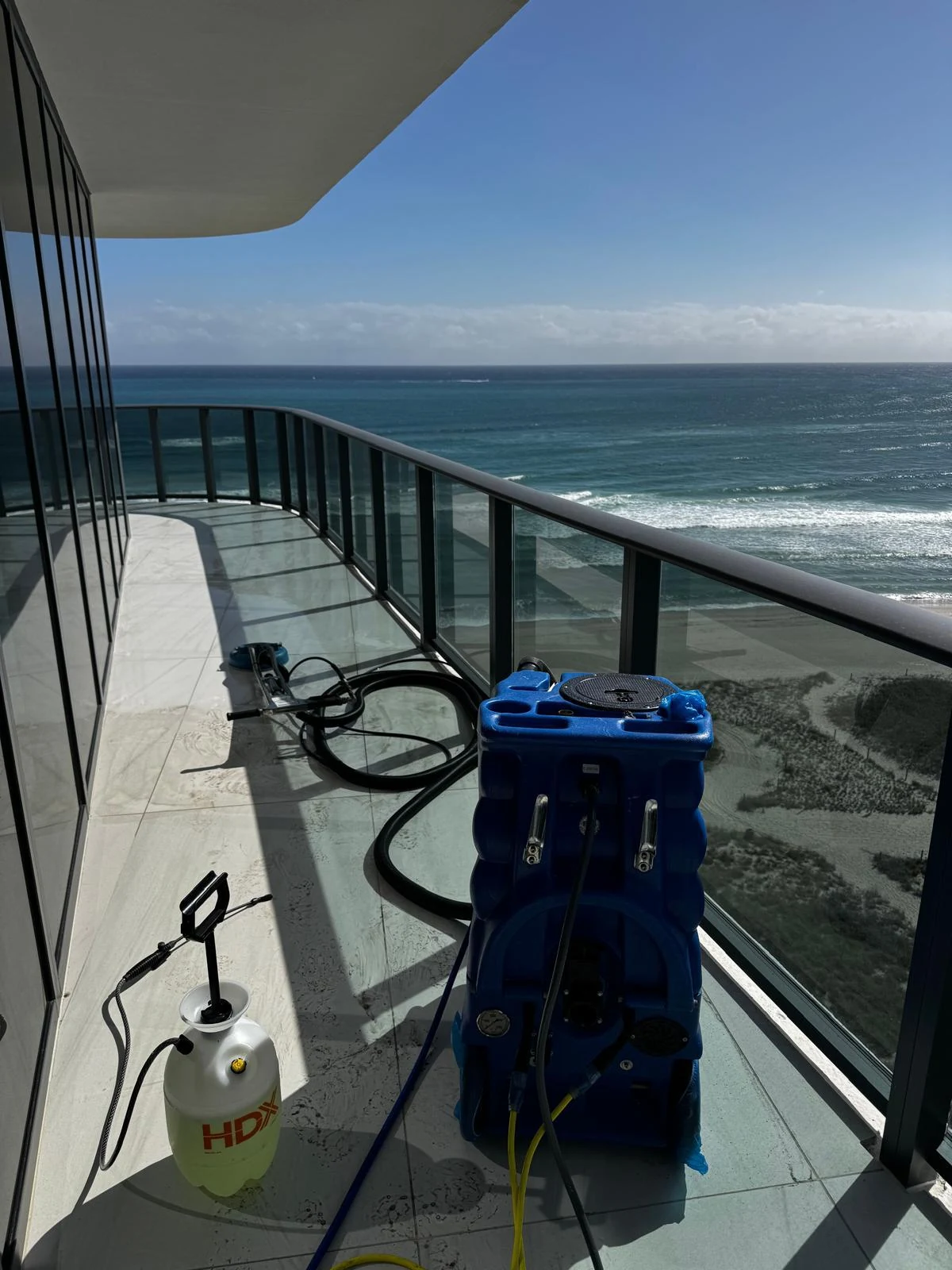 Residential balcony tile before cleaning with visible surface buildup and cleaning equipment present