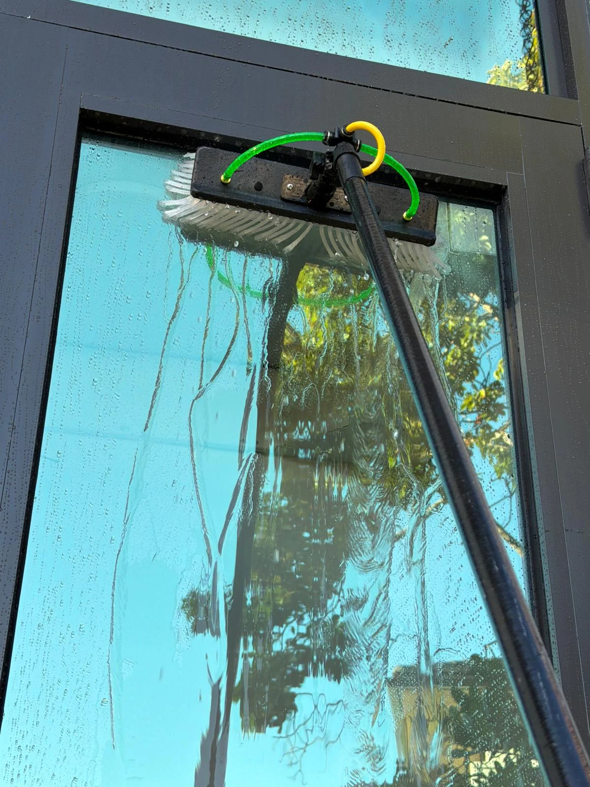 Fibratto technician using a brush on residential window glass during service