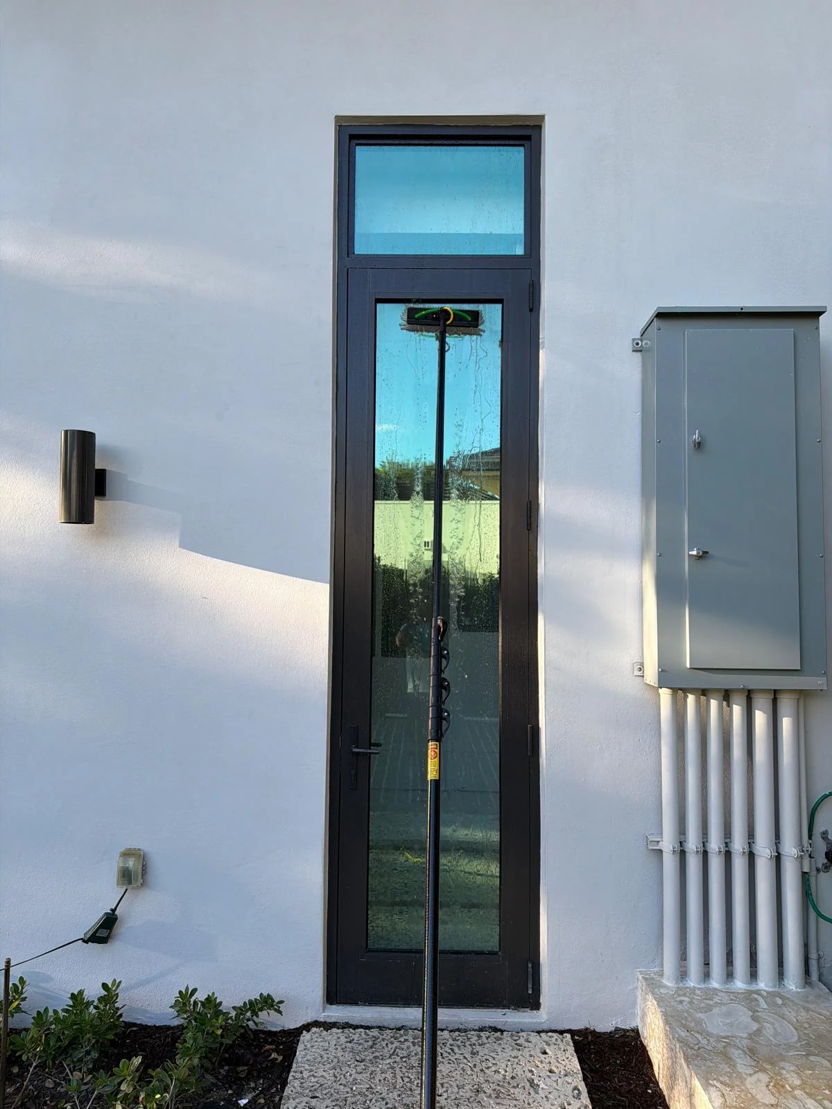 Fibratto technician cleaning a tall residential glass door during service